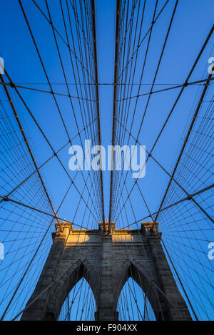 Brooklyn Bridge tower con doppio archi gotici e simmetrica dei cavi di sospensione al tramonto con il cielo azzurro, New York City Foto Stock