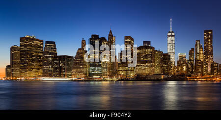 La città di New York skyline di Manhattan il quartiere finanziario al crepuscolo con grattacieli illuminati sollevandosi al di sopra di East River Foto Stock