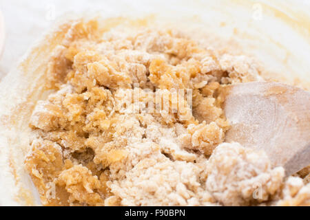 Close-up di pasta biscotto è mescolato con un cucchiaio di legno Foto Stock