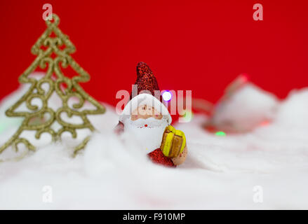 Babbo Natale figurine con dono su sfondo rosso Foto Stock