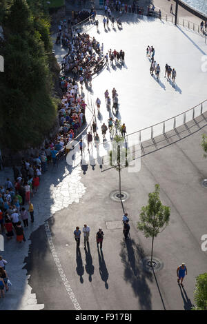 Pellegrini in un cue presso la grotta di Massabielle nel Santuario di Nostra Signora di Lourdes Foto Stock