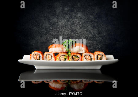 Il sushi e le bobine in piastra su uno sfondo nero Foto Stock