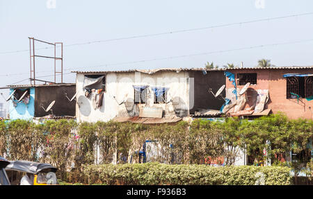 Tipico baraccopoli stradale alloggiamento con antenne paraboliche, Mumbai, India Foto Stock
