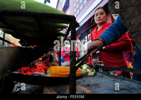 Kathmandu, Nepal. Xiii Dec, 2015. Kamala Subedi (blu maglione), 38 anni e Alisa Khadka (maglione rosso), 30 anni, residente permanente della Dolkha, funziona come un venditore ambulante a Kathmandu, vendita di mais tostato. Essi hanno utilizzato per acquistare materie granoturco a nr. 11 (US$ 0,11) per pezzo e poi venderlo torrefatto da 25 (US$ 0,25) per pezzo dove guadagnano la NRS 1500 (US$ 15) al giorno. © Narayan Maharjan/Pacific Press/Alamy Live News Foto Stock