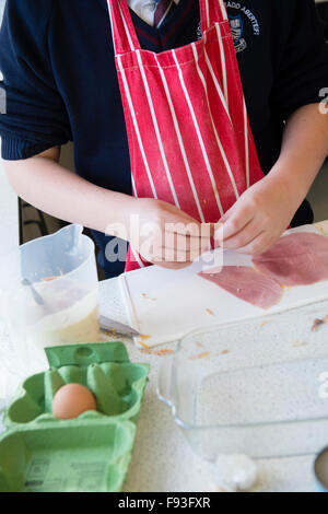 Istruzione secondaria Wales UK: Un ragazzo allievo studente la preparazione per la cottura di prodotti alimentari in una tecnologia alimentare (scienze domestiche) Scuola di insegnamento in aula di cucina Foto Stock