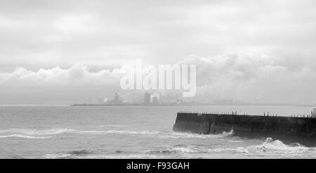 Vista del mare in tempesta a Hartlepool Headland con industriale Teesside in background in monocromia Foto Stock