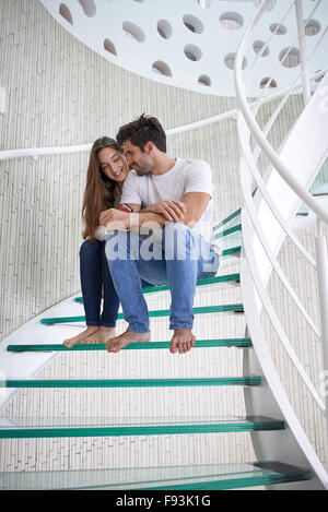 Rilassata giovane coppia in vetro a spirale scale in casa moderna villa in ambienti interni Foto Stock