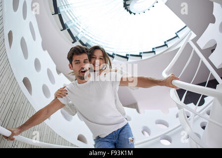 Rilassata giovane coppia in vetro a spirale scale in casa moderna villa in ambienti interni Foto Stock