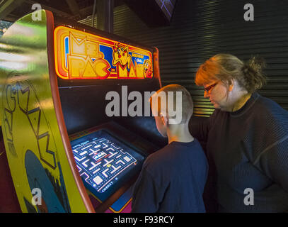 Città Giardino, New York, Stati Uniti d'America. 12 Dic, 2015. Un 6-anno-vecchio ragazzo riproduce il classico 1982 Bally/Midway arcade game Ms. Pac-Man, come membro della famiglia guarda, durante il giorno di apertura di età Arcade presentano in un set di arcade fino alla base del Museo dell'aviazione di Long Island. Ammissione include un numero illimitato di free pay-per-play di video giochi arcade. Presentano corre da Dic. 12, 2015 attraverso Aprile 3, 2016. © Ann Parry/ZUMA filo/Alamy Live News Foto Stock