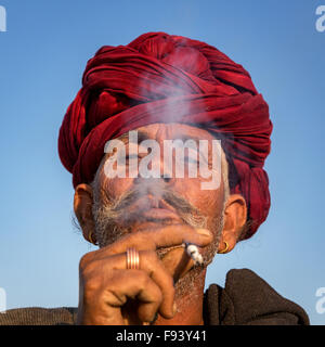 Ritratto di un senior di Rajasthani fumatori e con un turbante rosso, Pushkar, Rajasthan, India Foto Stock