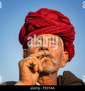 Ritratto di un senior di Rajasthani fumatori e con un turbante rosso, Pushkar, Rajasthan, India Foto Stock