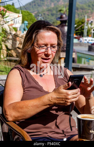 Donna di mezza età guardando uno Smartphone, Marmaris, Turchia Foto Stock