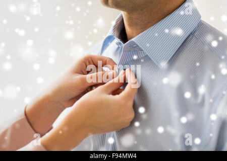 Close up di un uomo e di una donna di fissaggio pulsante camicia Foto Stock