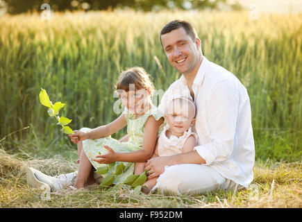 Felice giovane padre di trascorrere del tempo con il suo piccolo figlie nel verde della natura. Foto Stock