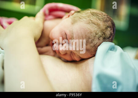 Bellissima bambina di pochi minuti dopo la nascita che giace sulla sua madre, pelle a contatto con la pelle Foto Stock