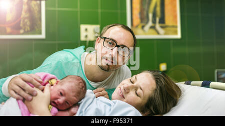 Bellissima bambina di pochi minuti dopo la nascita con la madre e il padre nella stanza di ospedale, pelle a contatto con la pelle Foto Stock