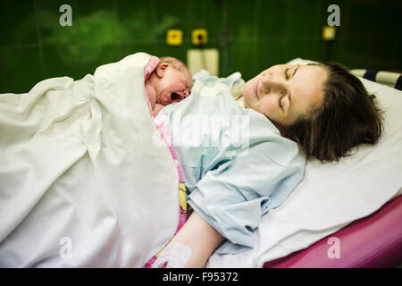 Bellissima bambina di pochi minuti dopo la nascita che giace sulla sua madre, pelle a contatto con la pelle Foto Stock