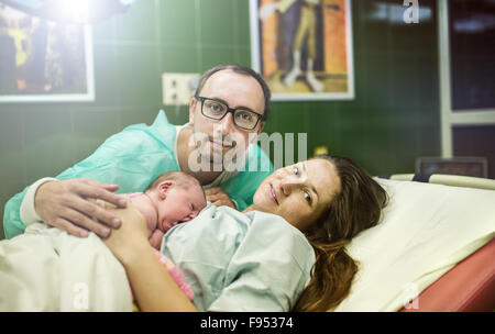 Bellissima bambina di pochi minuti dopo la nascita con la madre e il padre nella stanza di ospedale, pelle a contatto con la pelle Foto Stock