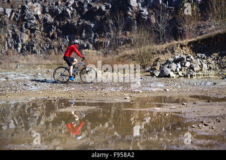 Ciclista uomo equitazione mountain bike lungo la pozza in cava Foto Stock