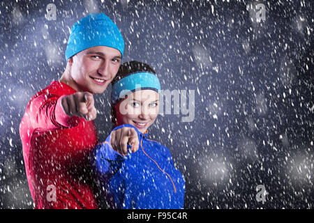 Giovani atleti fitness sono in piedi fuori in inverno freddo di notte. La neve è caduta intorno a. Foto Stock