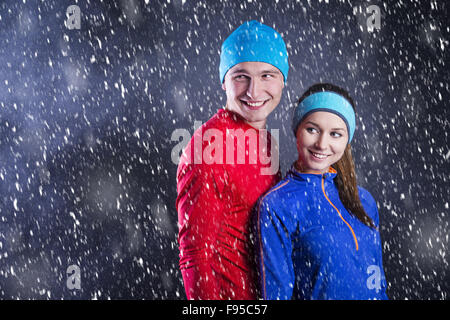 Giovani atleti fitness sono in piedi fuori in inverno freddo di notte. La neve è caduta intorno a. Foto Stock