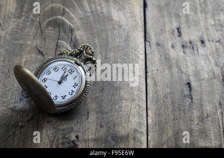 Antico orologio da tasca con catena contro rustico in legno invecchiato sfondo con mani quasi mezzanotte Foto Stock