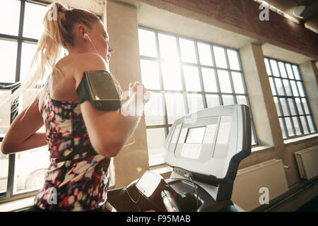 Giovane femmina focalizzato lavorando presso la palestra jogging su un tapis roulant. Donna Fitness facendo esercizio in esecuzione nel club salute. Foto Stock