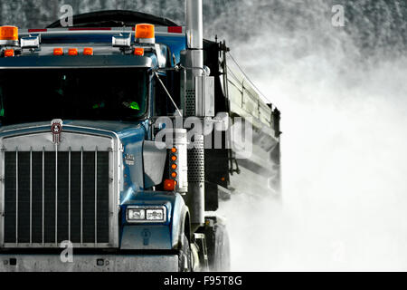 Un semi carrello di traino di un rimorchio su una coperta di neve strada creando un white out per gli altri automobilisti su un territorio rurale Alberta road Foto Stock