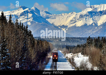 Un'immagine orizzontale di un Canadian National treno merci viaggiano attraverso le vette delle montagne rocciose di Alberta in Canada Foto Stock