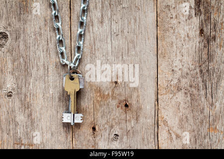 Chiavi appeso alla catena contro il vecchio muro di legno Foto Stock