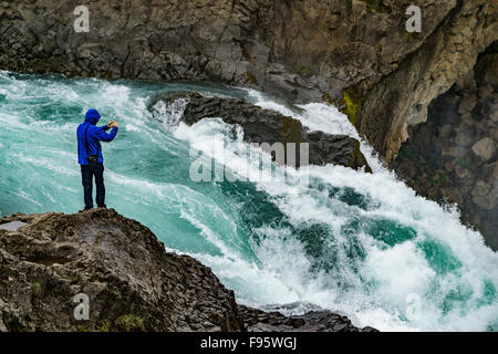 Uomo di scattare foto con uno smartphone a cascata Godafoss, Islanda Foto Stock