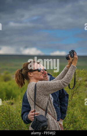 I turisti prendendo un selfie a cascata Hraunfossar, Islanda Foto Stock