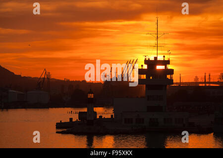 Sagome di gru e di edifici nel porto di Varna al tramonto Foto Stock