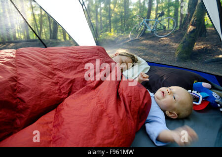 Una giovane madre e il suo unico anno vecchio ragazzo in una tenda su un viaggio di campeggio. La mamma sta ancora cercando di dormire. Rosebery Parco Provinciale, Foto Stock