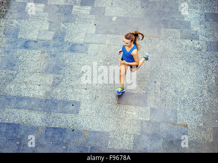 Angolo di Alta Vista del giovane femmina runner jogging sul pavimento piastrellato di vecchia città sul centro. Foto Stock