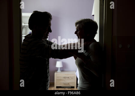 Silhouette di Coppia matura combattimenti, l uomo è fisicamente abusando della donna. La donna è vittima di violenza domestica Foto Stock