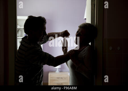 Silhouette di Coppia matura combattimenti, l uomo è fisicamente abusando della donna. La donna è vittima di violenza domestica Foto Stock