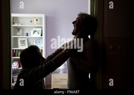 Silhouette di Coppia matura combattimenti, l uomo è fisicamente abusando della donna. La donna è vittima di violenza domestica Foto Stock