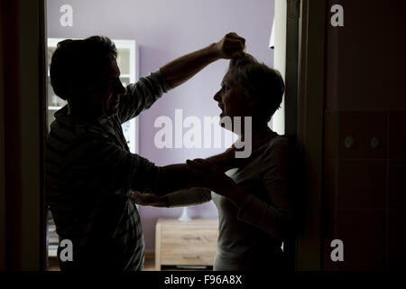 Silhouette di Coppia matura combattimenti, l uomo è fisicamente abusando della donna. La donna è vittima di violenza domestica Foto Stock