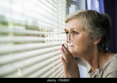 La paura della donna si cerca attraverso la finestra. Avente livido sul suo viso Foto Stock