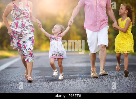 La famiglia felice avendo divertimento durante il cammino sulla strada Foto Stock