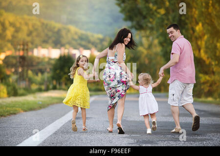 La famiglia felice avendo divertimento durante il cammino sulla strada Foto Stock