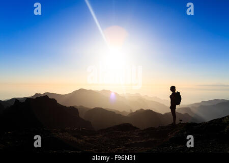 Donna silhouette di escursioni in montagna, tramonto e oceano. Escursionista femmina sulla cima della montagna guardando bella notte inspirati al tramonto Foto Stock