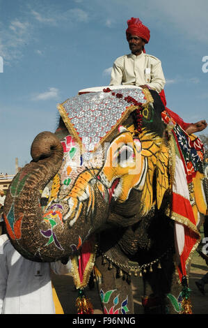 Decorate elephant dipinta con una immagine di Lion con i cervi nella sua bocca sulla faccia con il suo padrone a Jaipur, Rajasthan, India. Foto Stock