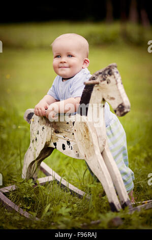 Carino piccolo ragazzo sul cavallo a dondolo al di fuori Foto Stock