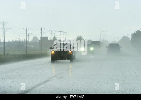 Una pesante pioggia tempesta sbatte la carreggiata rendendo visability molto scarsa la guida in una piccola città nello stato di Alberta, Canada Foto Stock