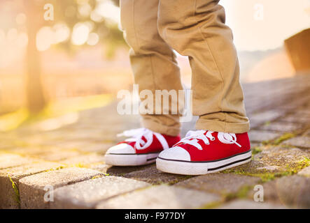 Close-up di Little Boy in piedi sul pavimento piastrellato in estate park Foto Stock