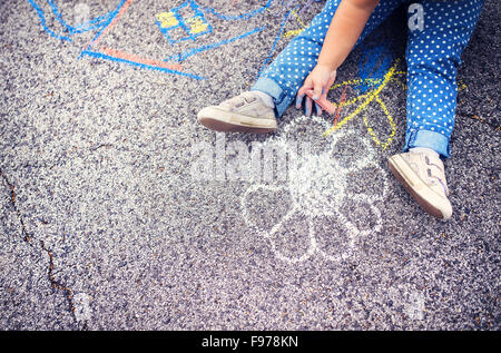 Close up della bambina in scarpe di tela disegno con gessi sul marciapiede Foto Stock