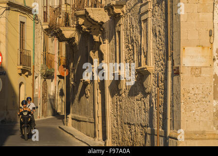 Via Sicilia, vista di persone a cavallo di uno scooter in una tipica stradina nel centro storico (Centro Storico) di isola di Ortigia, Siracusa, Sicilia. Foto Stock