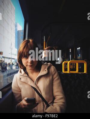 Ritratto di giovane donna utilizzando il telefono cellulare mentre si è in viaggio in tram